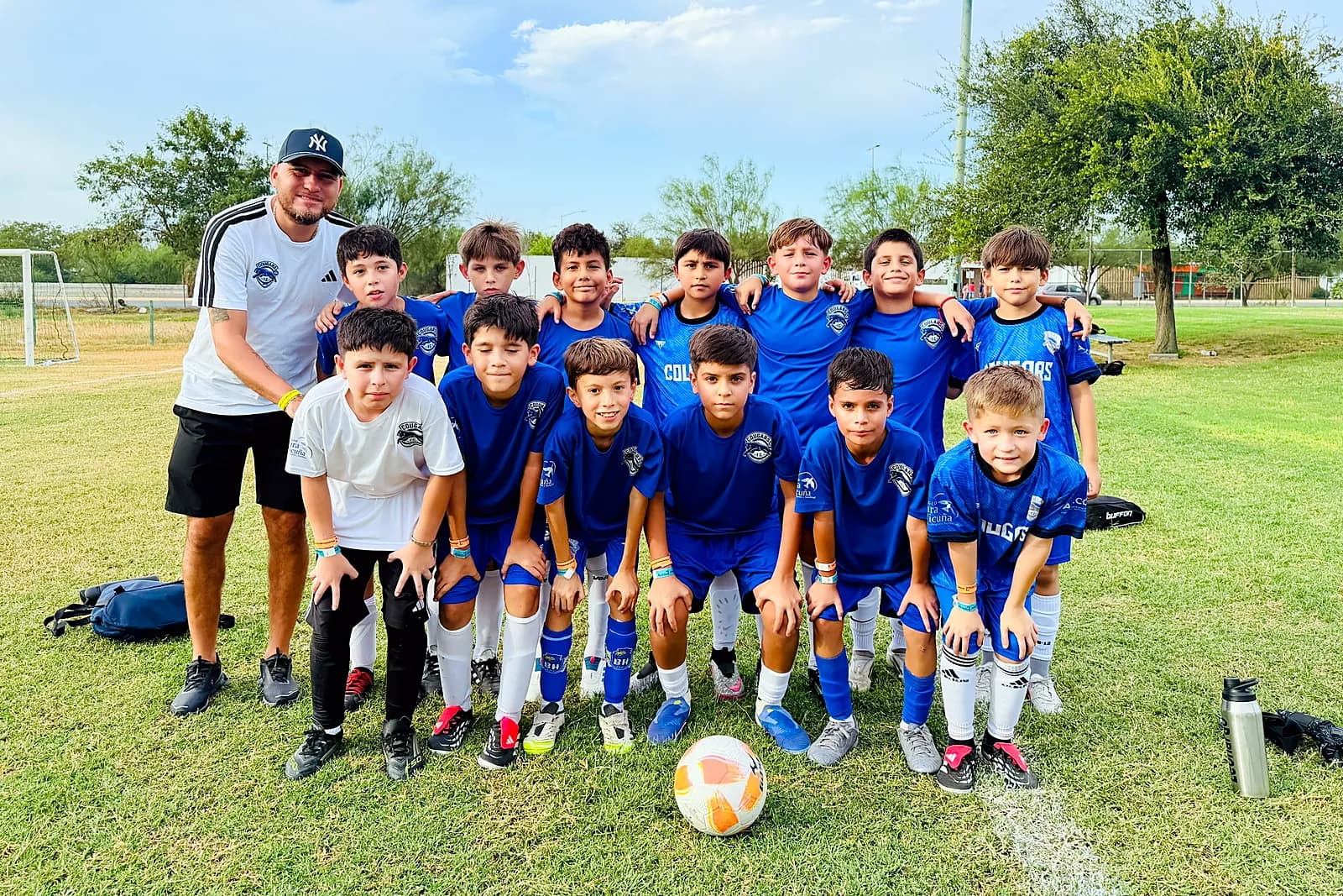 Jugadores de Cougars FC posando con su entrenador en la cancha