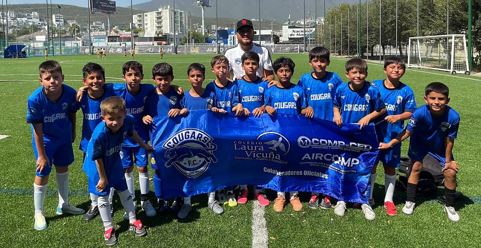 Equipo de Cougars FC con la manta de patrocinadores y el Cerro de la Silla al fondo